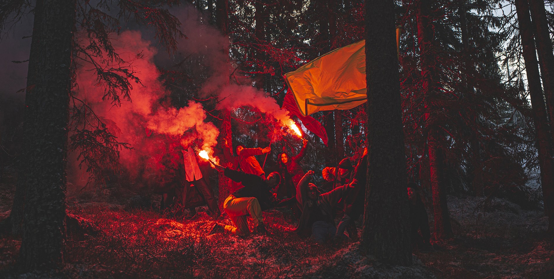Dansare från det samtida danskompaniet Norrdans dansar i en skog med rök och signalljus