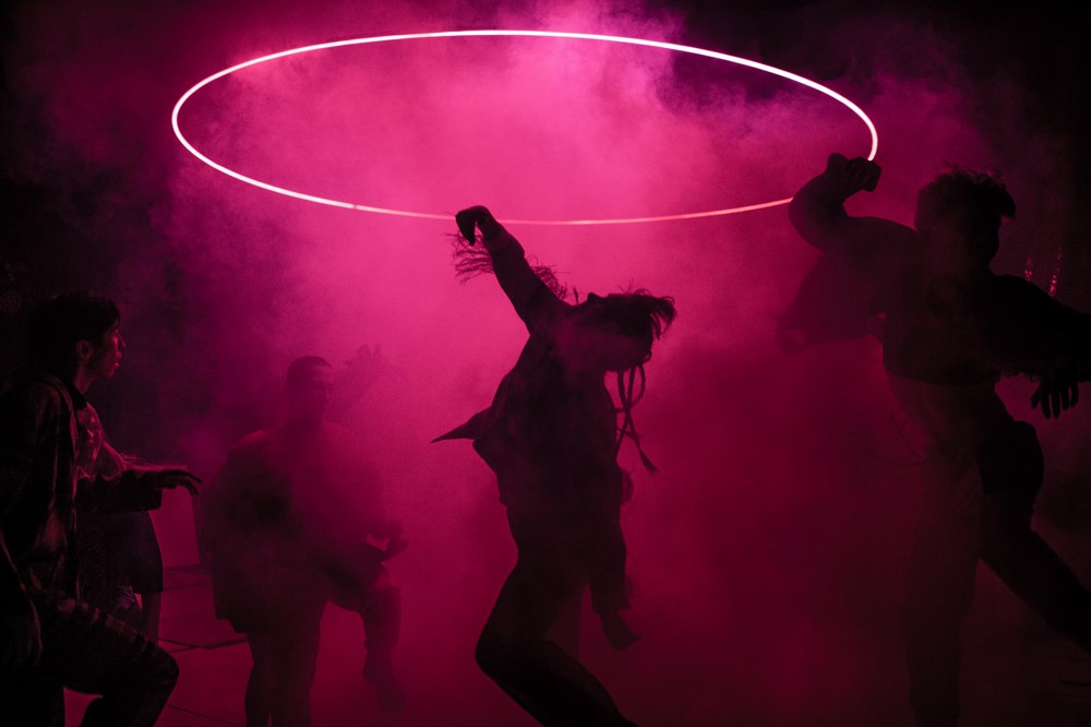 Dansare från det samtida danskompaniet Norrdans dansar med rök i rosa ljus.