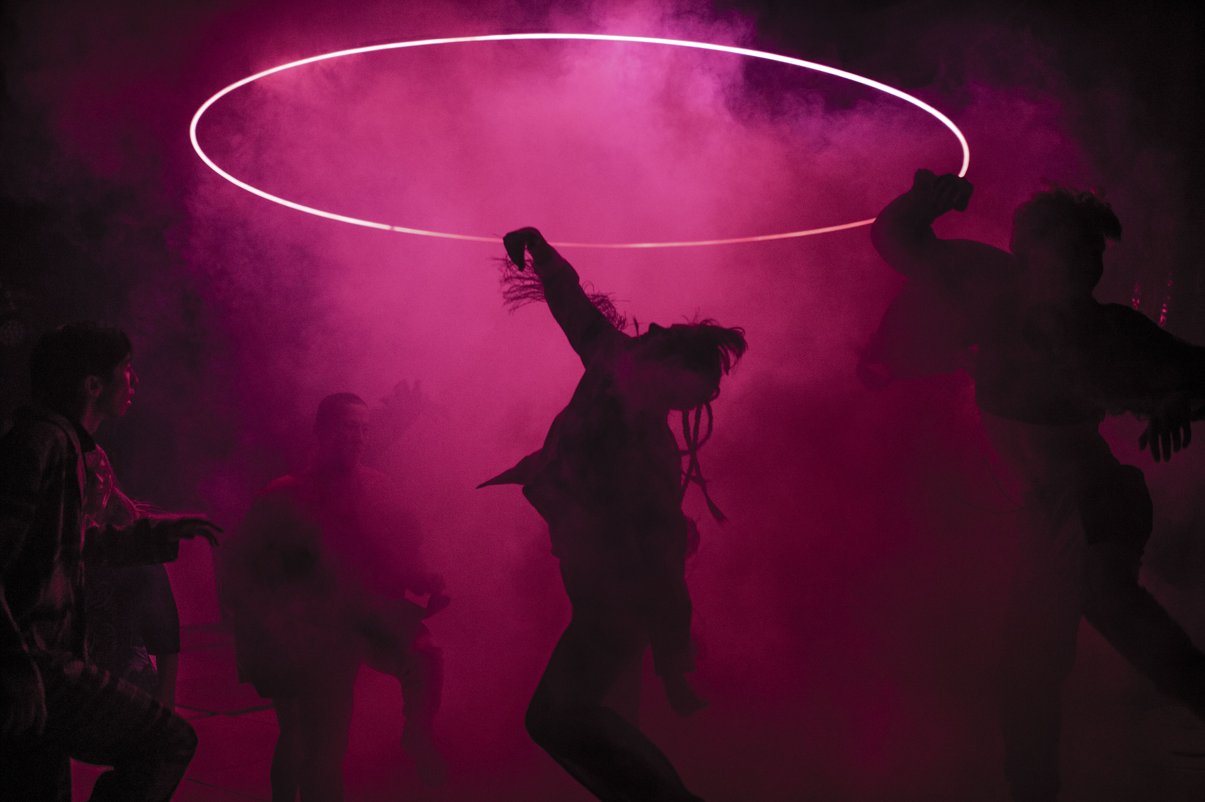 Dansare från det samtida danskompaniet Norrdans dansar med rök i rosa ljus.