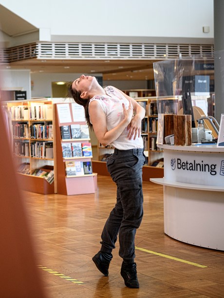Ensam dansare framför den samtida dansföreställningen If Only I Knew på ett bibliotek