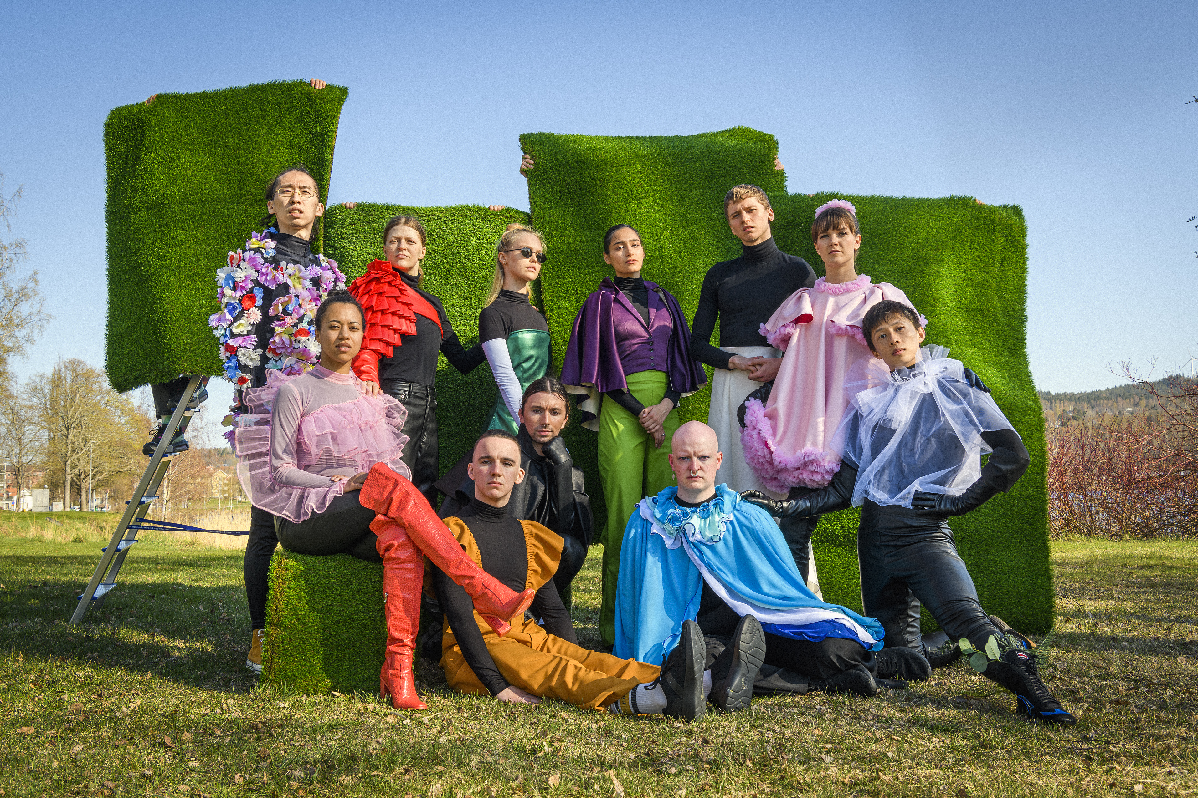 Norrdans dansare poserar i färgglad kostym utomhus framför konstgräs för Norrdans samtida dansföreställning VÅR VÅR!