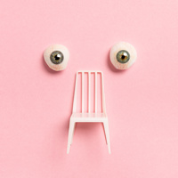 Affisch bild till Norrdans samtida dansföreställning ONE ONE ONE. Två stirrande ögon och en stol på rosa bakgrund.