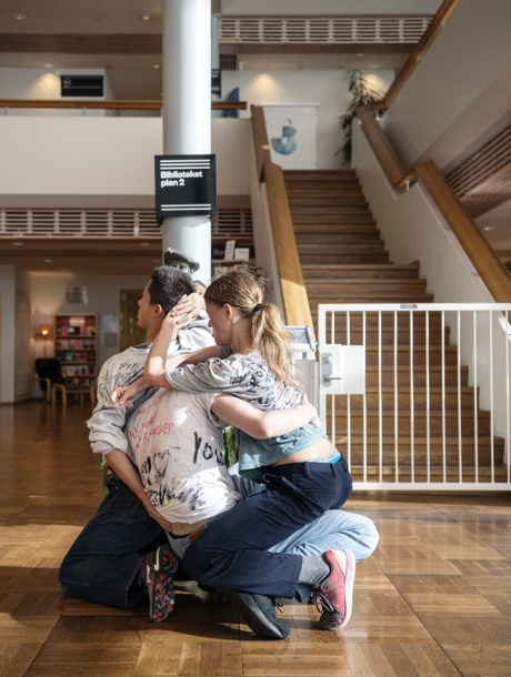 Tre dansare omfamnar varandra i ett bibliotek i den samtida dansföreställningen If Only I Knew.