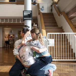 Tre dansare omfamnar varandra i ett bibliotek i den samtida dansföreställningen If Only I Knew.
