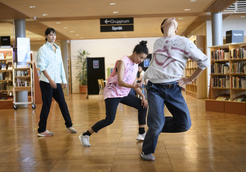 Tre dansare framför den samtida dansföreställningen If Only I Knew på ett bibliotek